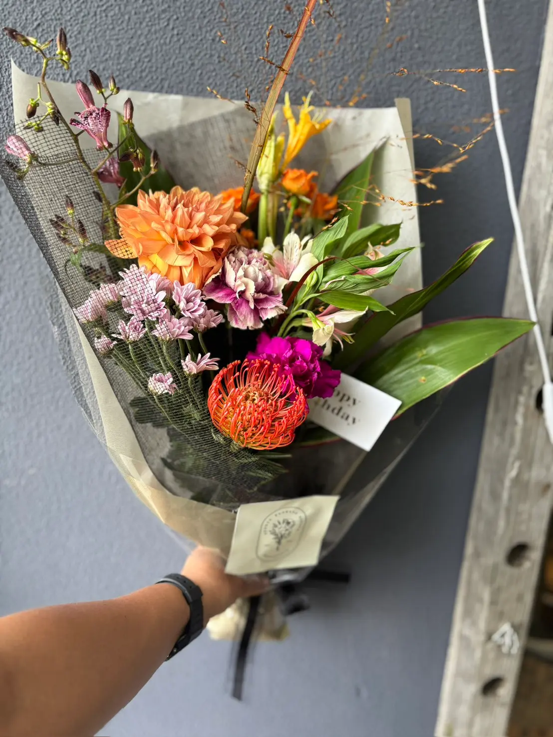 ダリアとプロテアを黒の紙で包んだ、誕生日の花束