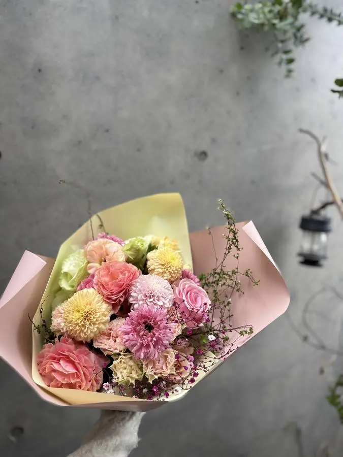 ピンクと淡黄の花を、淡い紙で包んだ季節の花束